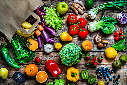 Grocery bag and food items on a wood table
